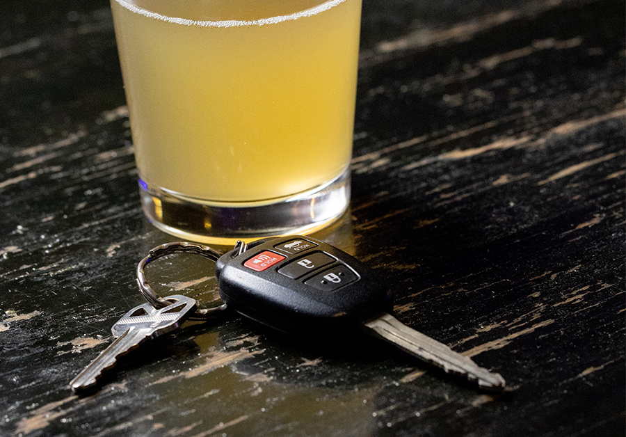 a set of car keys sitting in front of a glass of beer on a bar