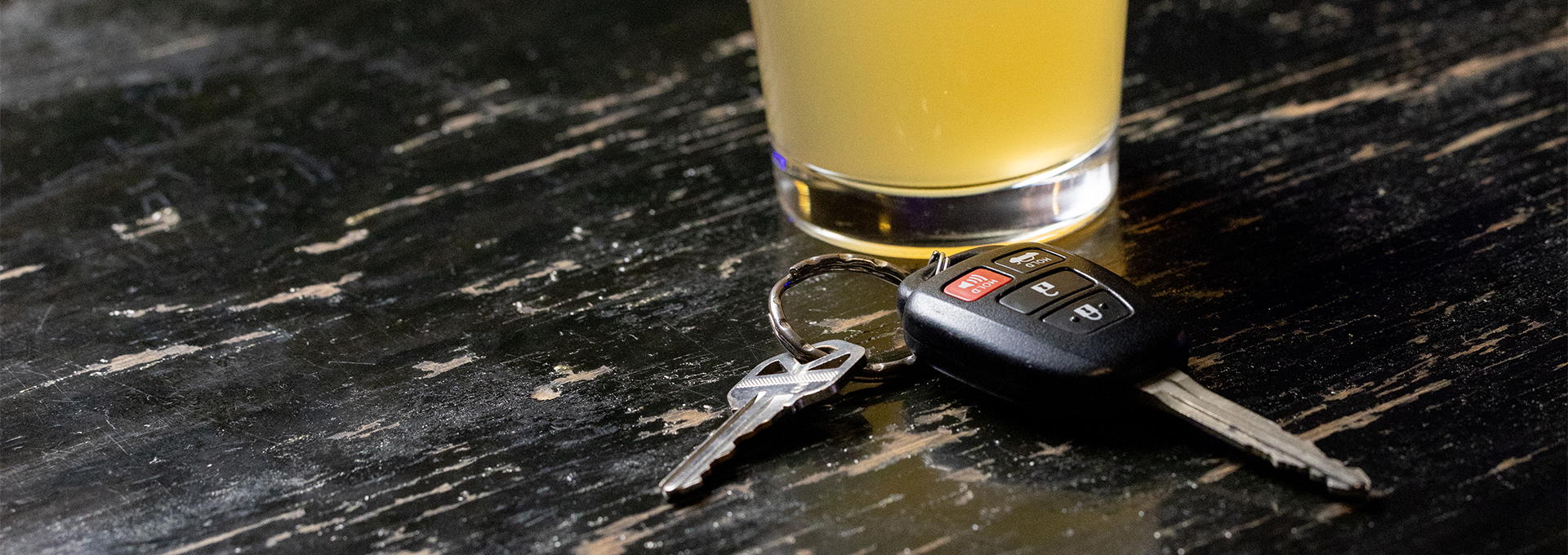 a set of car keys sitting in front of a glass of beer on a bar